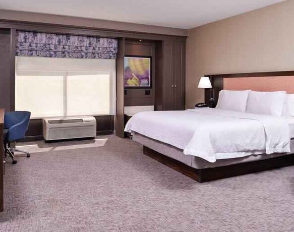 Spacious and bright king guestroom with window and desk at the Hampton Inn Albuquerque, University-Midtown (UNM).