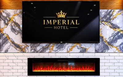 Elegant lobby feature wall at Imperial Hotel showcasing the hotel's branding above a contemporary fireplace, accented with marble-inspired finishes and warm ambient lighting that create a welcoming first impression for guests.