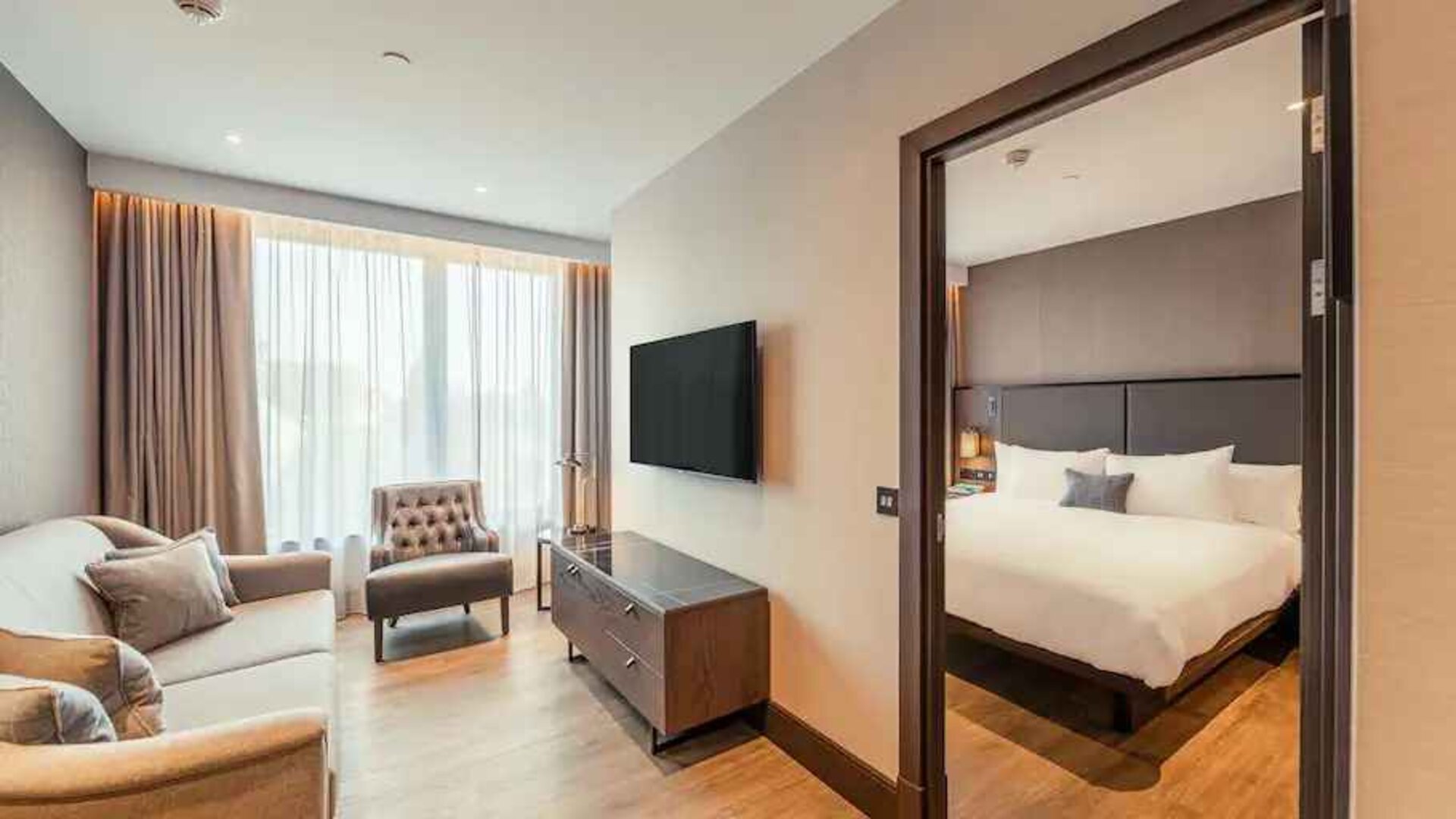 Living room with sofa and TV screen at the Fellows House Cambridge, Curio Collection by Hilton.