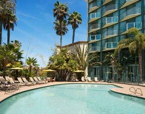beautiful outdoor pool surrounded by greenery and with comfortable sun beds at DoubleTree by Hilton Hotel San Diego - Hotel Circle.