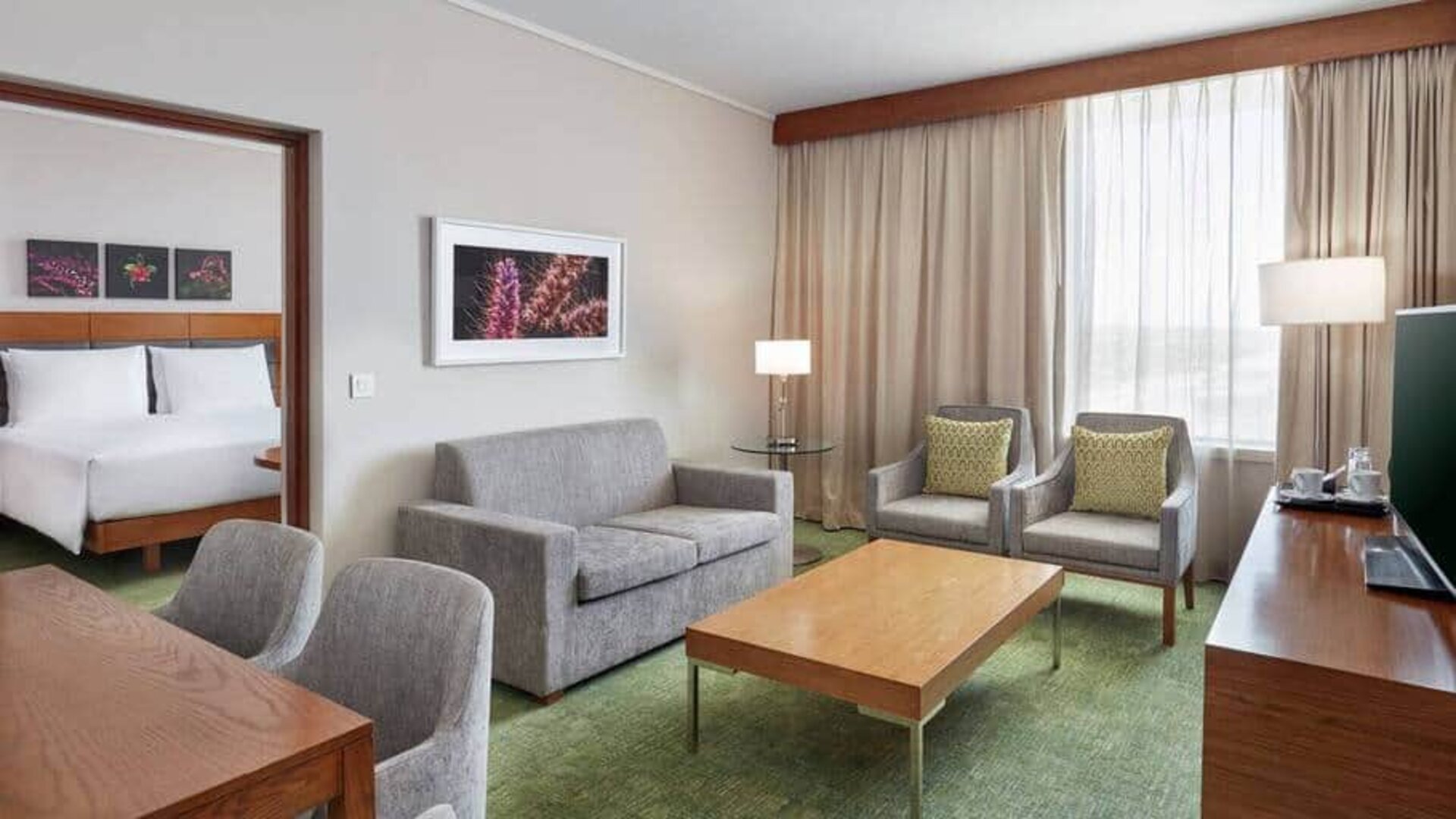 Double-room view of king-size bed and separate seating area with couch, coffee table and TV.