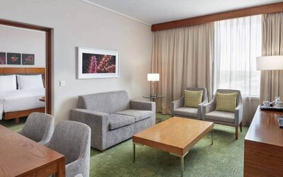 Double-room view of king-size bed and separate seating area with couch, coffee table and TV.