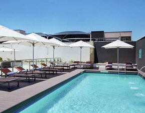 Narrow rectangular pool with fountains coming out of side wall, abundant lounge chairs for sunbathing.