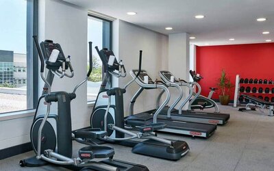 Ellipticals, treadmills, and space for free weights in hotel exercise room.