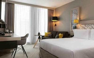 King bedroom with desk and sofa at the Hilton Garden Inn Bordeaux Centre.