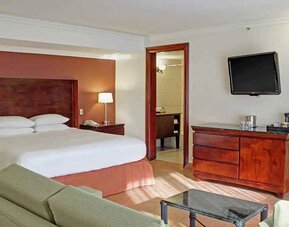 luxurious king suite with TV, work desk, and lounge area at DoubleTree by Hilton Hotel Cariari San Jose - Costa Rica.