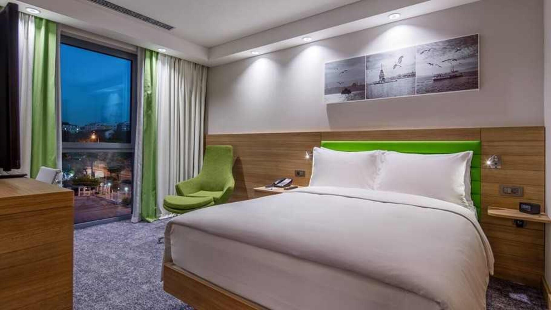 comfortable king bed with work desk and large windows at Hampton by Hilton Istanbul Zeytinburnu.