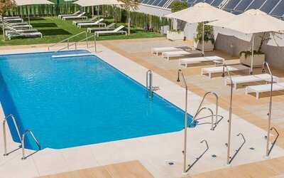 stunning outdoor pool with sun beds and umbrellas at Hilton Garden Inn Sevilla.