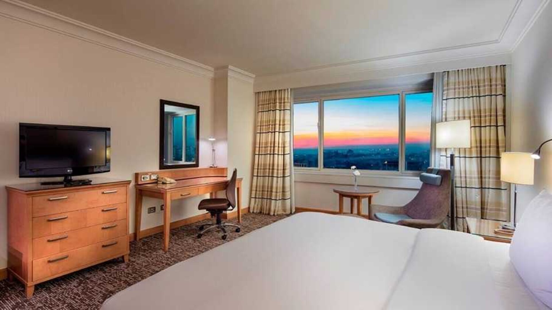 lovely king bedroom with TV, desk, and chair at Adana HiltonSA.