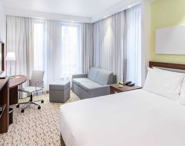 Queen room with sofa, desk and TV screen at the Hampton by Hilton Gdansk Oliwa.