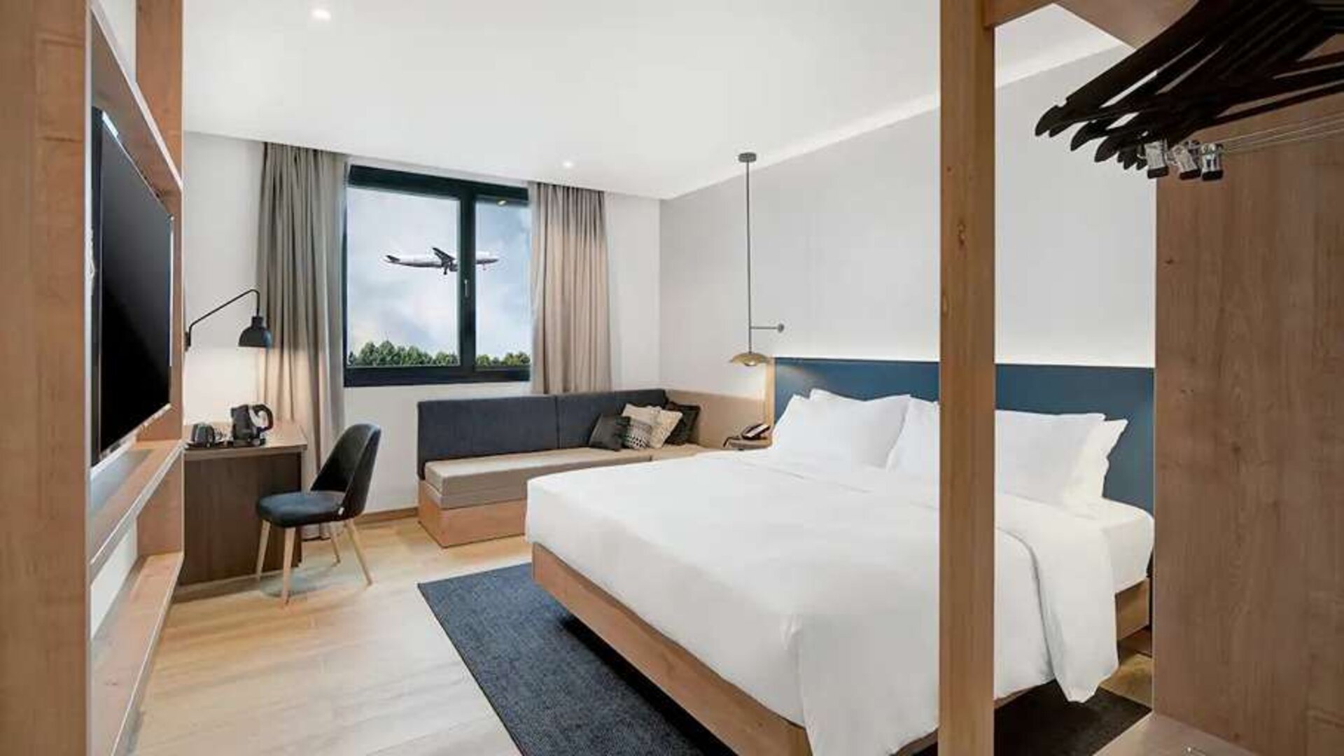 spacious king bedroom with TV, desk, chair, and couch at Hilton Garden Inn Bucharest Airport.