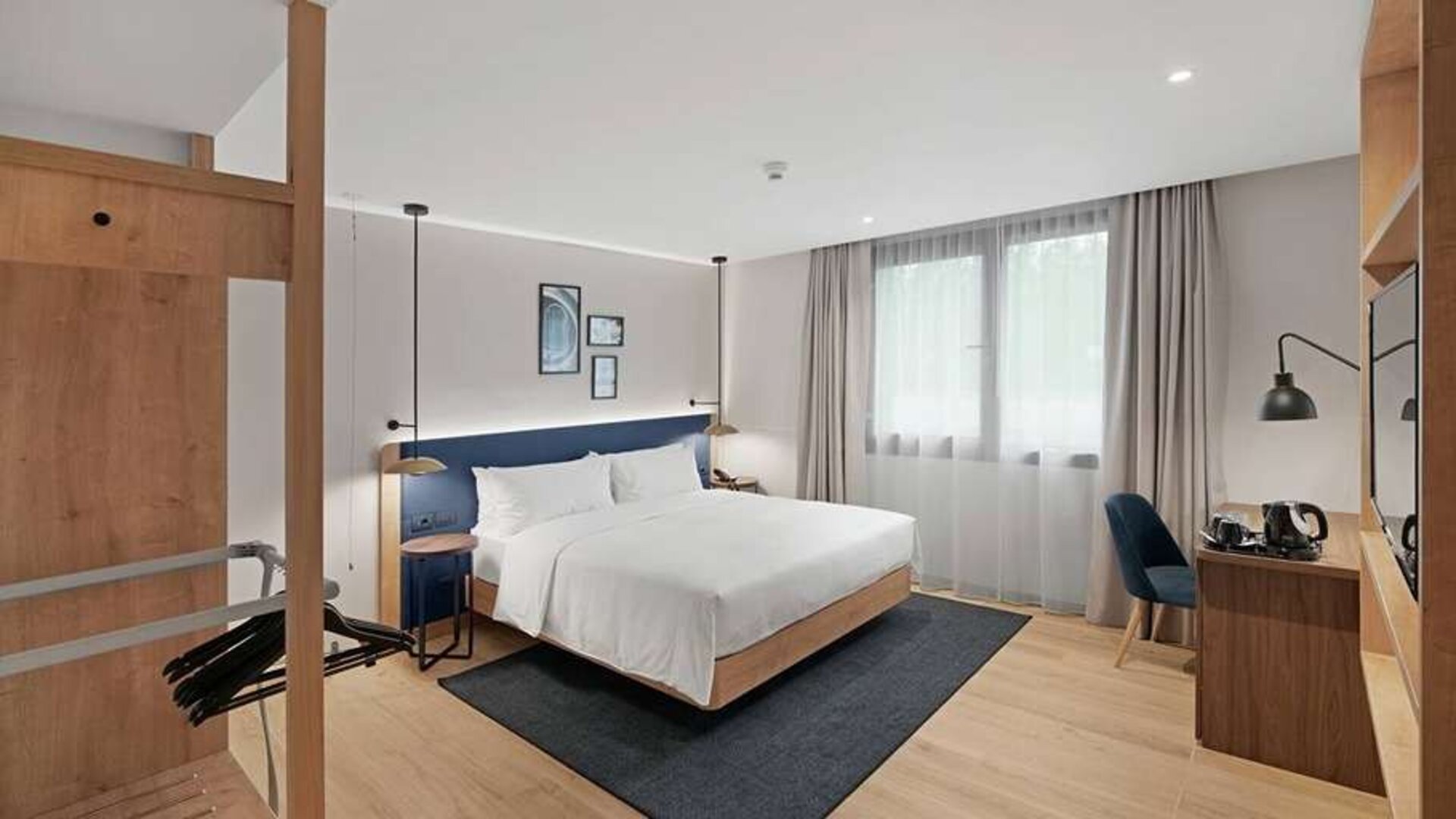 standard king room with chair, desk and TV at Hilton Garden Inn Bucharest Airport.