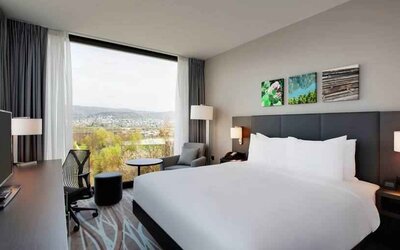 Bright king bedroom with desk along the window at the Hilton Garden Inn Zurich Limmattal.