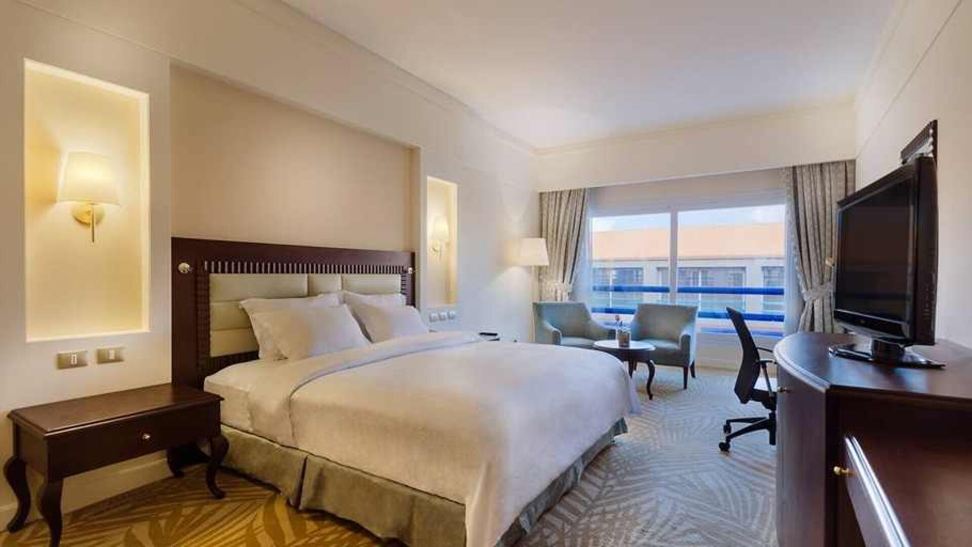 lovely king suite with TV, lounge area, work desk, and chair at Hilton Alexandria Green Plaza.