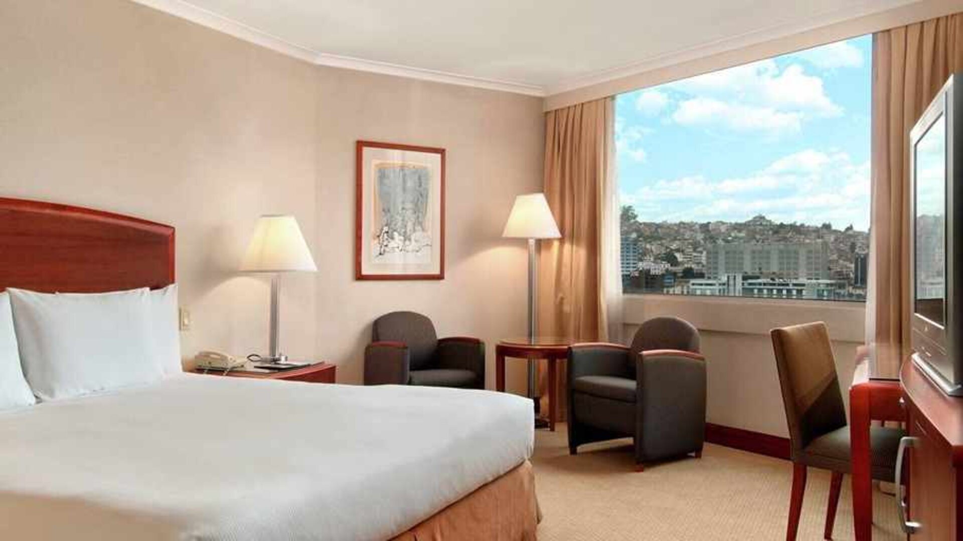 comfortable king room with TV, desk, chair, and couches at Hilton Colon Quito.