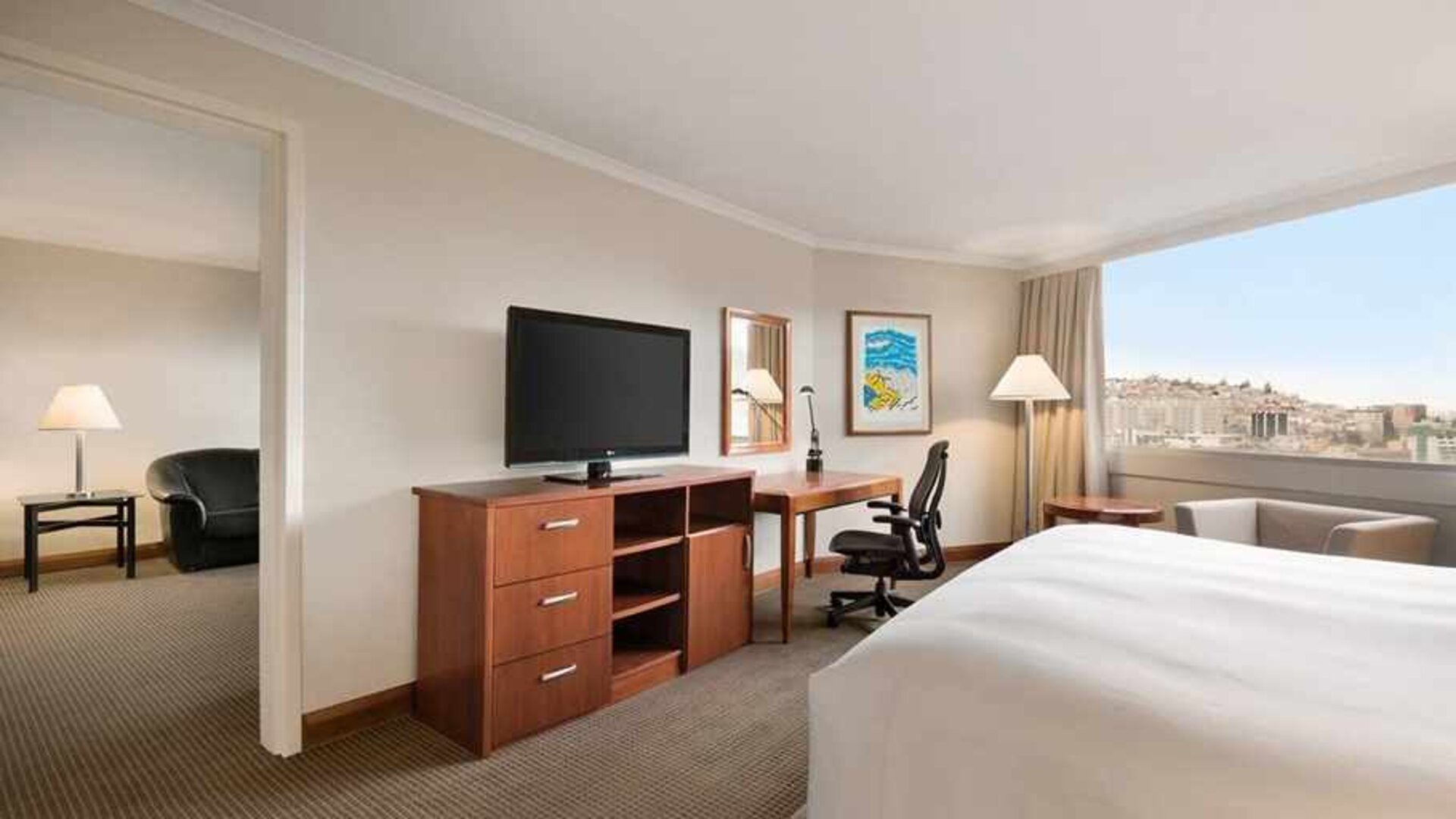 spacious king suite with TV, desk, chair, and couch at Hilton Colon Quito.