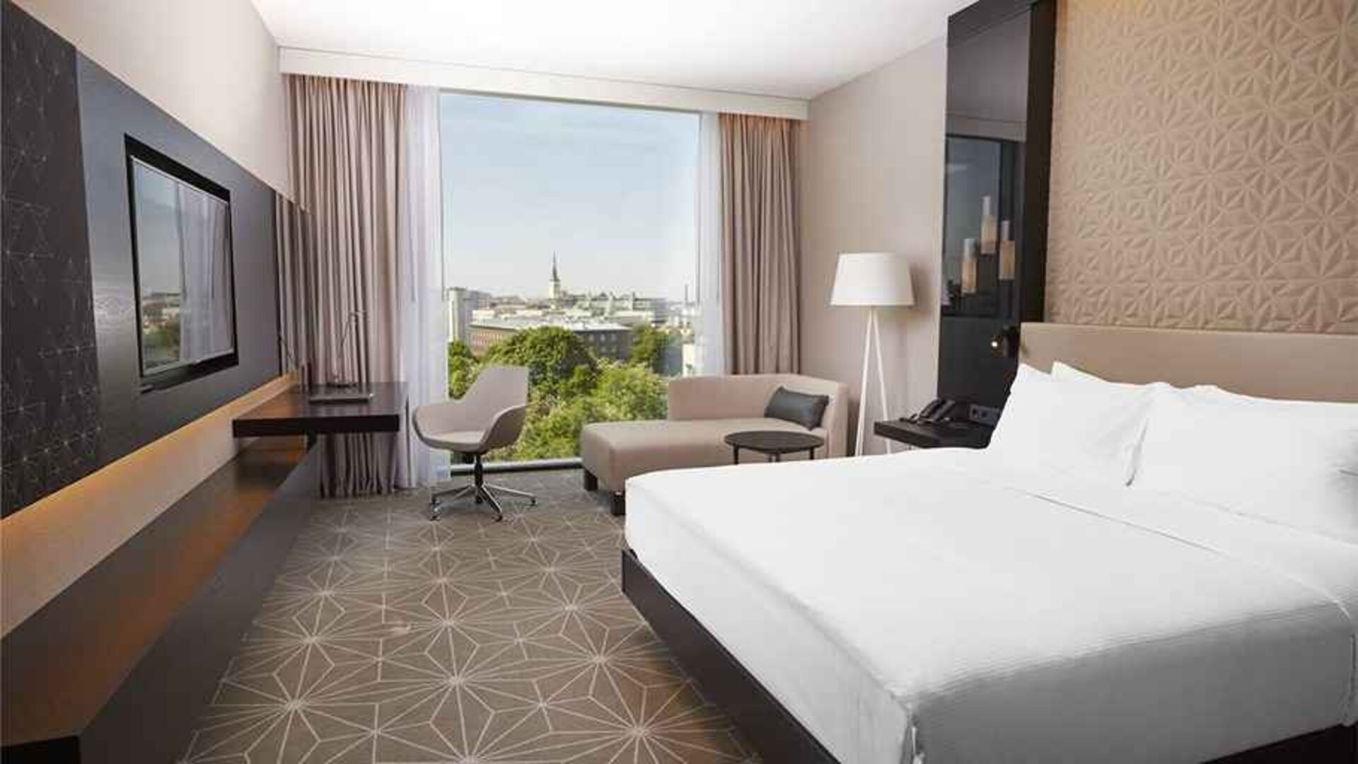 spacious king room with TV, desk, chair, and couch at Hilton Tallinn Park.