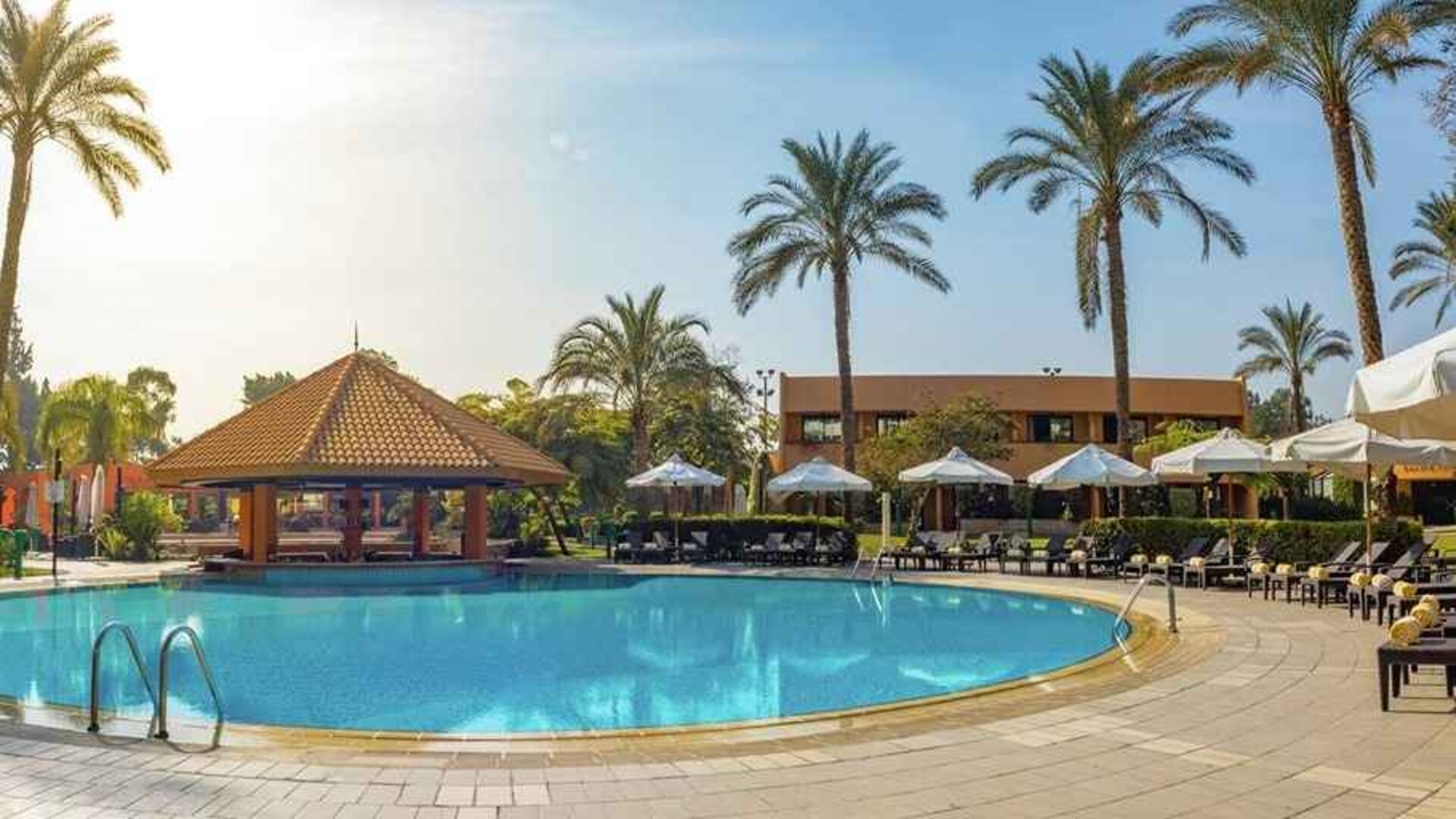stunning outdoor pool with sunbeds and umbrellas at Hilton Cairo Heliopolis.