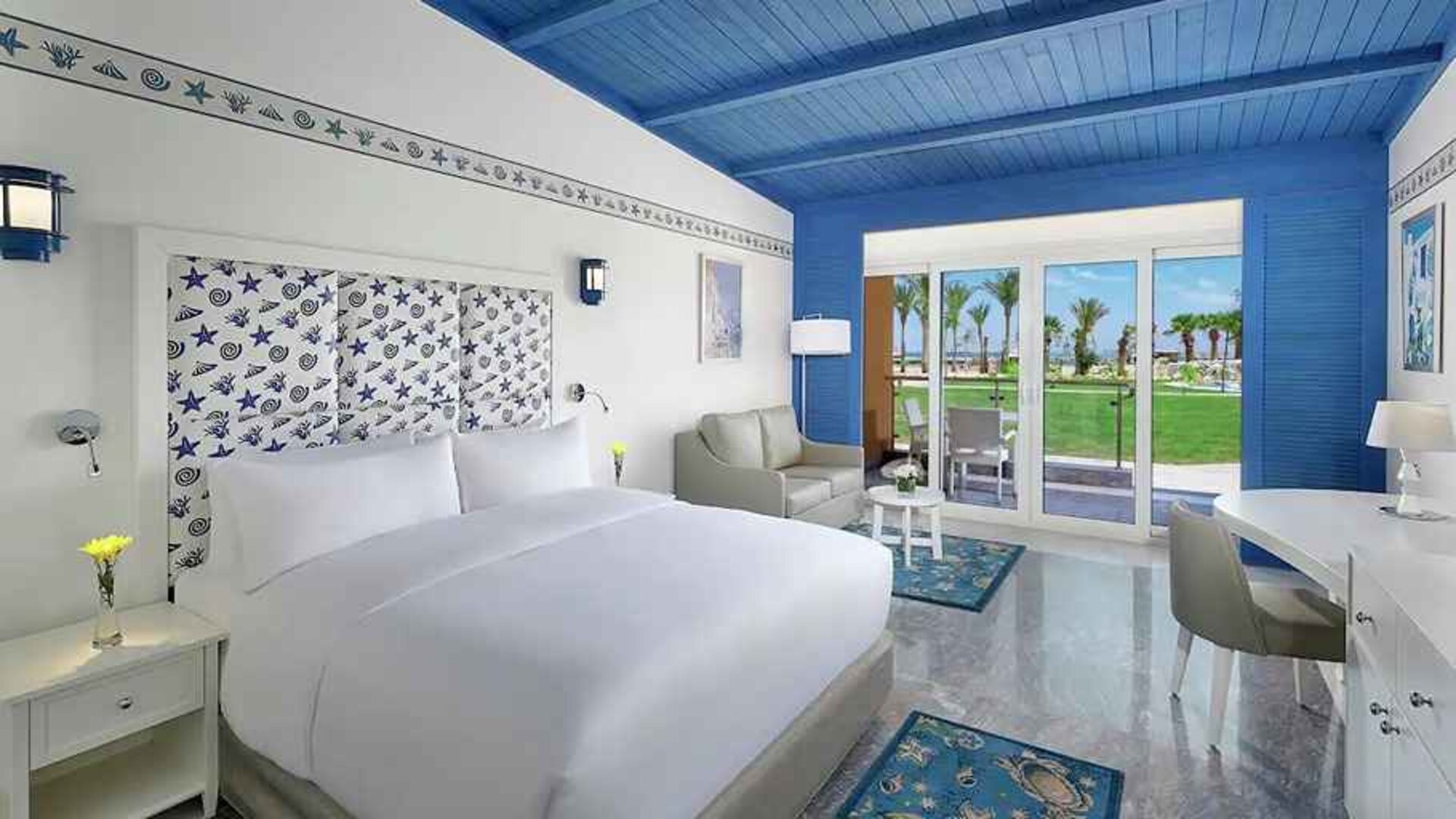 spacious king suite with desk, chair, couch, and outdoor terrace at Hilton Hurghada Plaza.