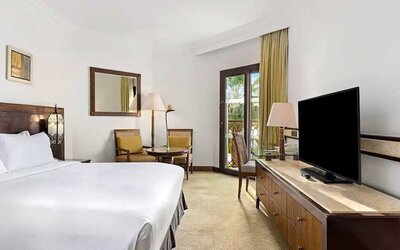 spacious king suite with TV, desk, chair, and dining area at Hilton Luxor Resort & Spa.