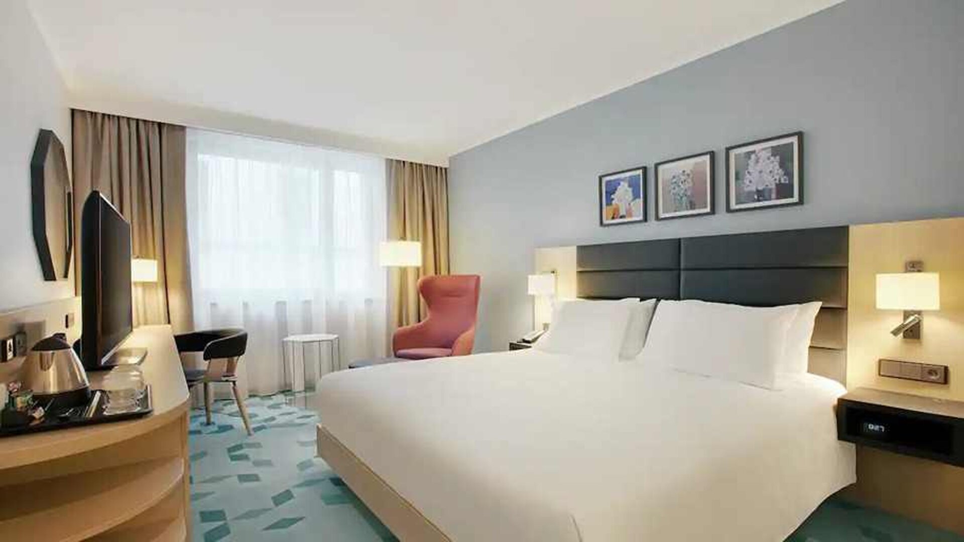 delux king room with TV, desk, chair, and couch at Hilton Garden Inn Budapest City Centre.