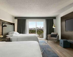 Double queen room with TV screen at the Embassy Suites by Hilton Los Angeles Downey.