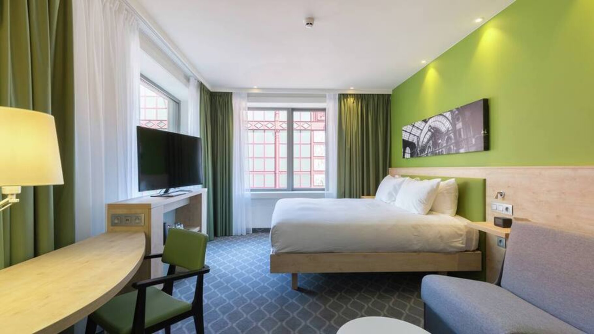 Lime green walls and a chic city view complement this king-size bed with workspace and television hotel room.