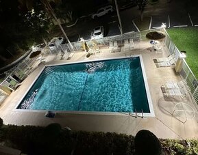 Outdoor swimming pool surrounded by lounge seating, offering guests a relaxing place to unwind and enjoy Florida's warm weather at La Quinta Inn & Suites By Wyndham Sawgrass Mills.