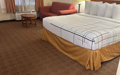 Spacious guest room with a king-size bed, seating area, and ample floor space, offering comfort and convenience for both business and leisure travelers.