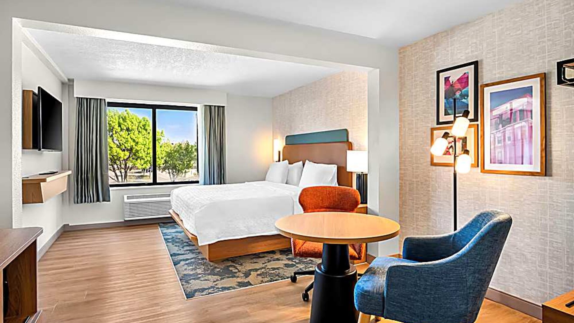Spacious king room with chair and table and TV. 