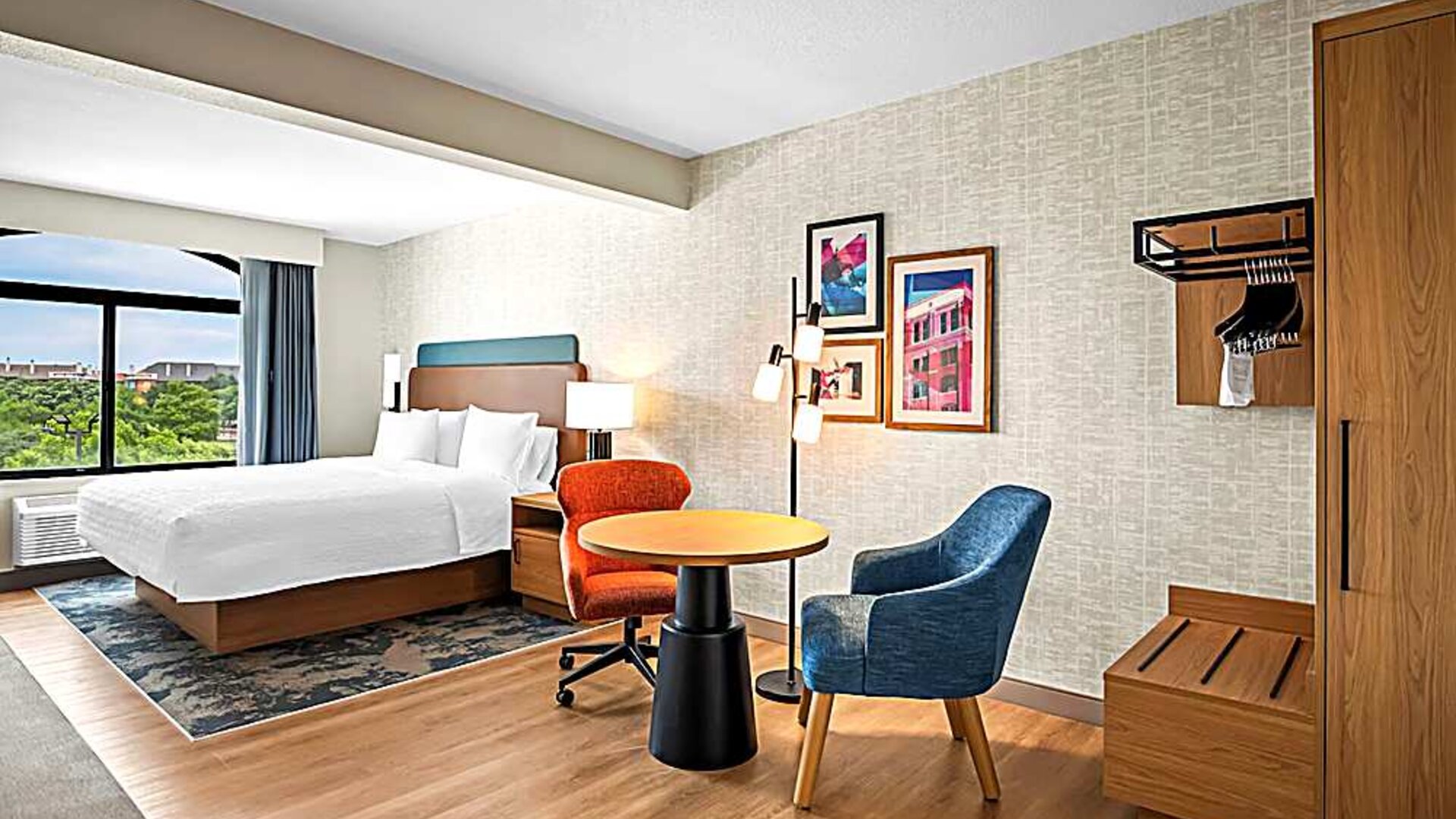 Spacious king room with chair and table and TV. 
