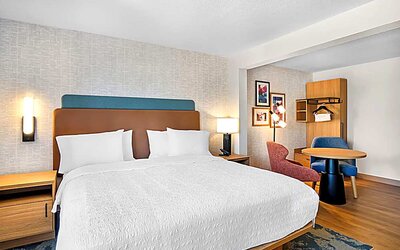 Romantic king bed with seating area Spacious king room with chair and table and TV. 