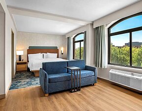 Spacious king room with sofa and large windows Spacious king room with chair and table and TV. 