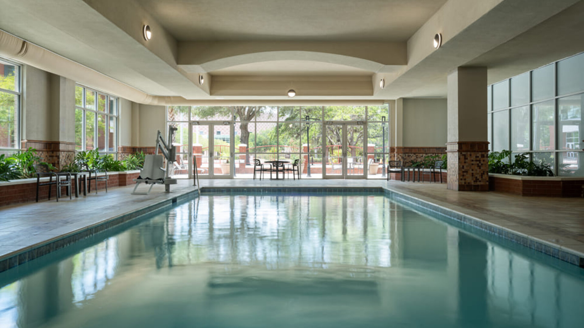 Indoor swimming pool with natural light, lounge seating, and a relaxing atmosphere at Embassy Suites By Hilton Charleston Airport Convention Center.