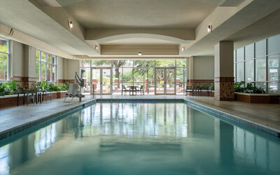 Indoor swimming pool with natural light, lounge seating, and a relaxing atmosphere at Embassy Suites By Hilton Charleston Airport Convention Center.