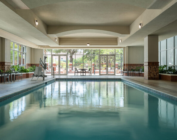 Indoor swimming pool with natural light, lounge seating, and a relaxing atmosphere at Embassy Suites By Hilton Charleston Airport Convention Center.