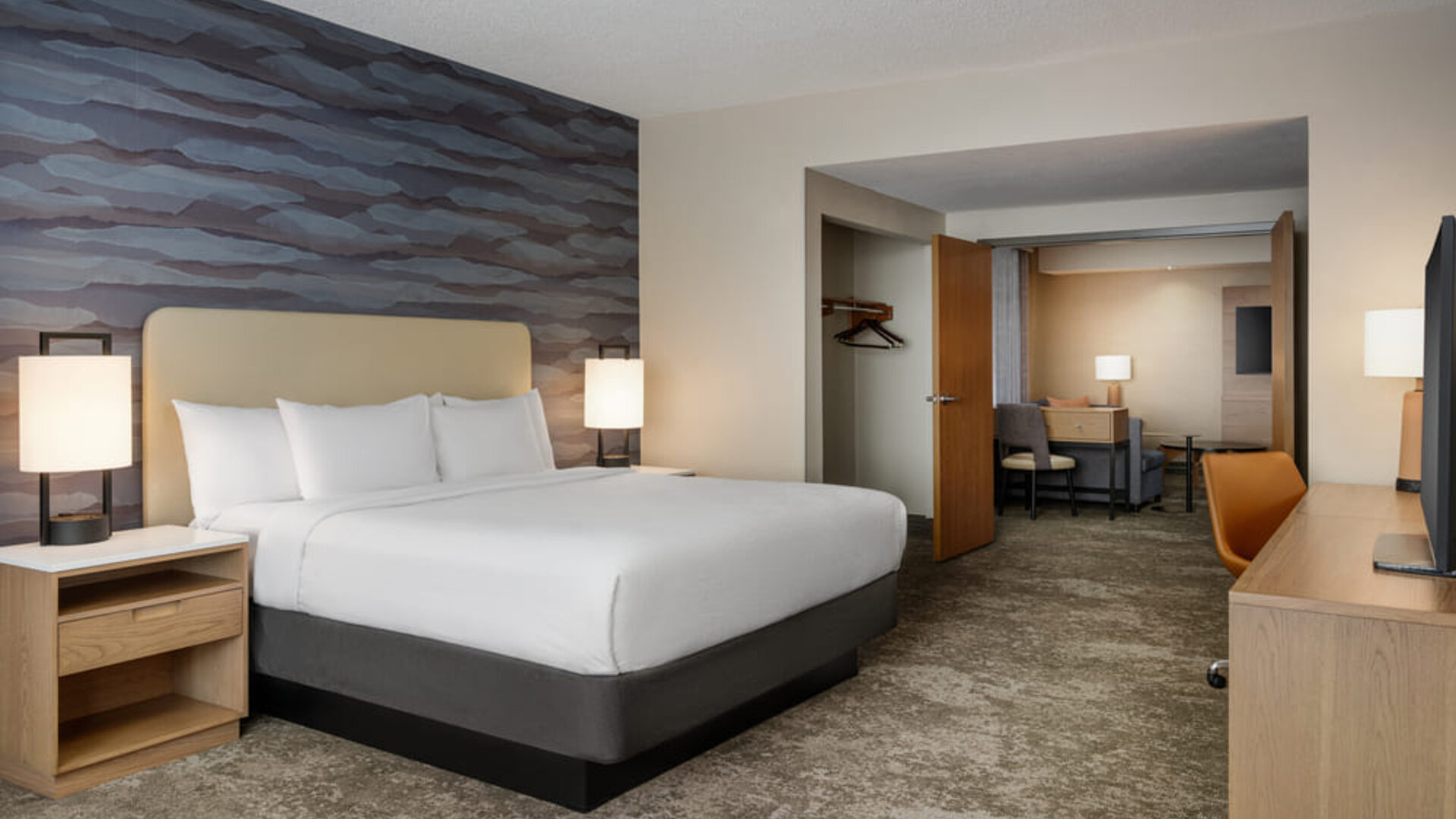 Spacious king guest room with contemporary décor, plush bedding, work area, and separate seating space at Embassy Suites By Hilton Charleston Airport Convention Center.