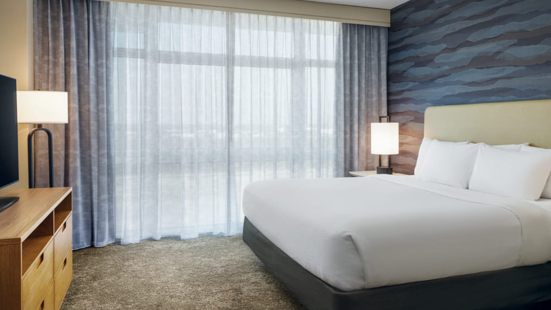 Bright king guest room with contemporary décor, spacious layout, and abundant natural light at Embassy Suites By Hilton Charleston Airport Convention Center.