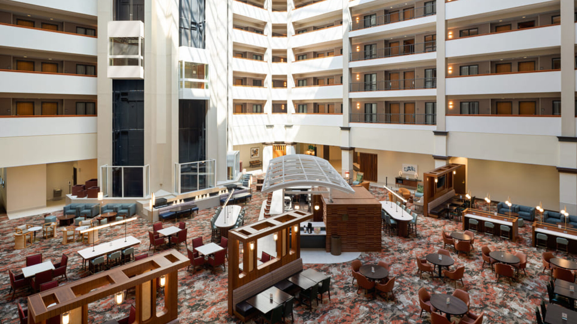 Open-air atrium featuring multiple guest room levels, comfortable seating areas, and a bright, welcoming atmosphere at Embassy Suites By Hilton Charleston Airport Convention Center.