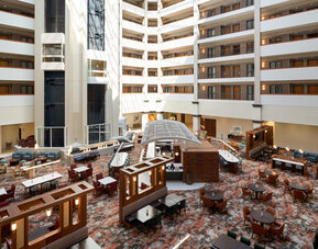 Open-air atrium featuring multiple guest room levels, comfortable seating areas, and a bright, welcoming atmosphere at Embassy Suites By Hilton Charleston Airport Convention Center.