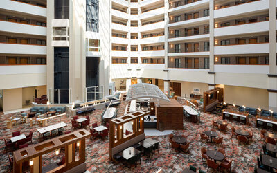 Open-air atrium featuring multiple guest room levels, comfortable seating areas, and a bright, welcoming atmosphere at Embassy Suites By Hilton Charleston Airport Convention Center.