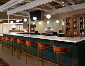 Stylish hotel bar offering comfortable seating, premium beverages, and a contemporary social setting at Embassy Suites By Hilton Charleston Airport Convention Center.