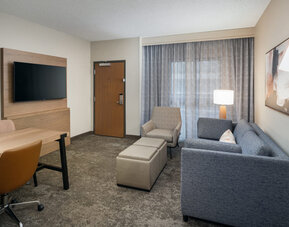 Suite living area featuring a sofa, workspace, flat-screen television, and comfortable seating for extended stays at Embassy Suites By Hilton Charleston Airport Convention Center.
