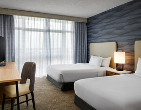 Guest room with two comfortable beds, modern furnishings, and floor-to-ceiling windows providing abundant natural light at Embassy Suites By Hilton Charleston Airport Convention Center.