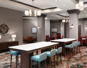 Comfortable dining and lounge area with communal seating, modern furnishings, and an inviting atmosphere at Embassy Suites By Hilton Charleston Airport Convention Center.