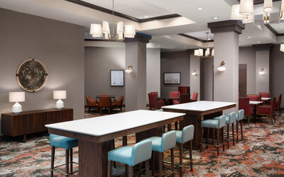 Comfortable dining and lounge area with communal seating, modern furnishings, and an inviting atmosphere at Embassy Suites By Hilton Charleston Airport Convention Center.
