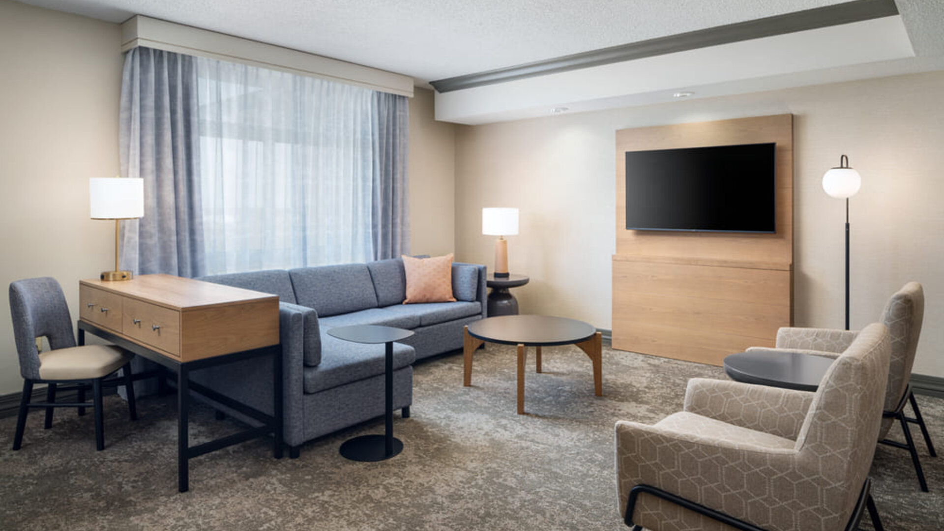 Suite living room with comfortable seating, workspace, and entertainment area designed for relaxation and productivity at Embassy Suites By Hilton Charleston Airport Convention Center.