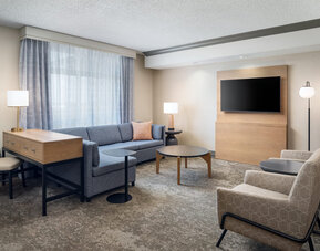 Suite living room with comfortable seating, workspace, and entertainment area designed for relaxation and productivity at Embassy Suites By Hilton Charleston Airport Convention Center.