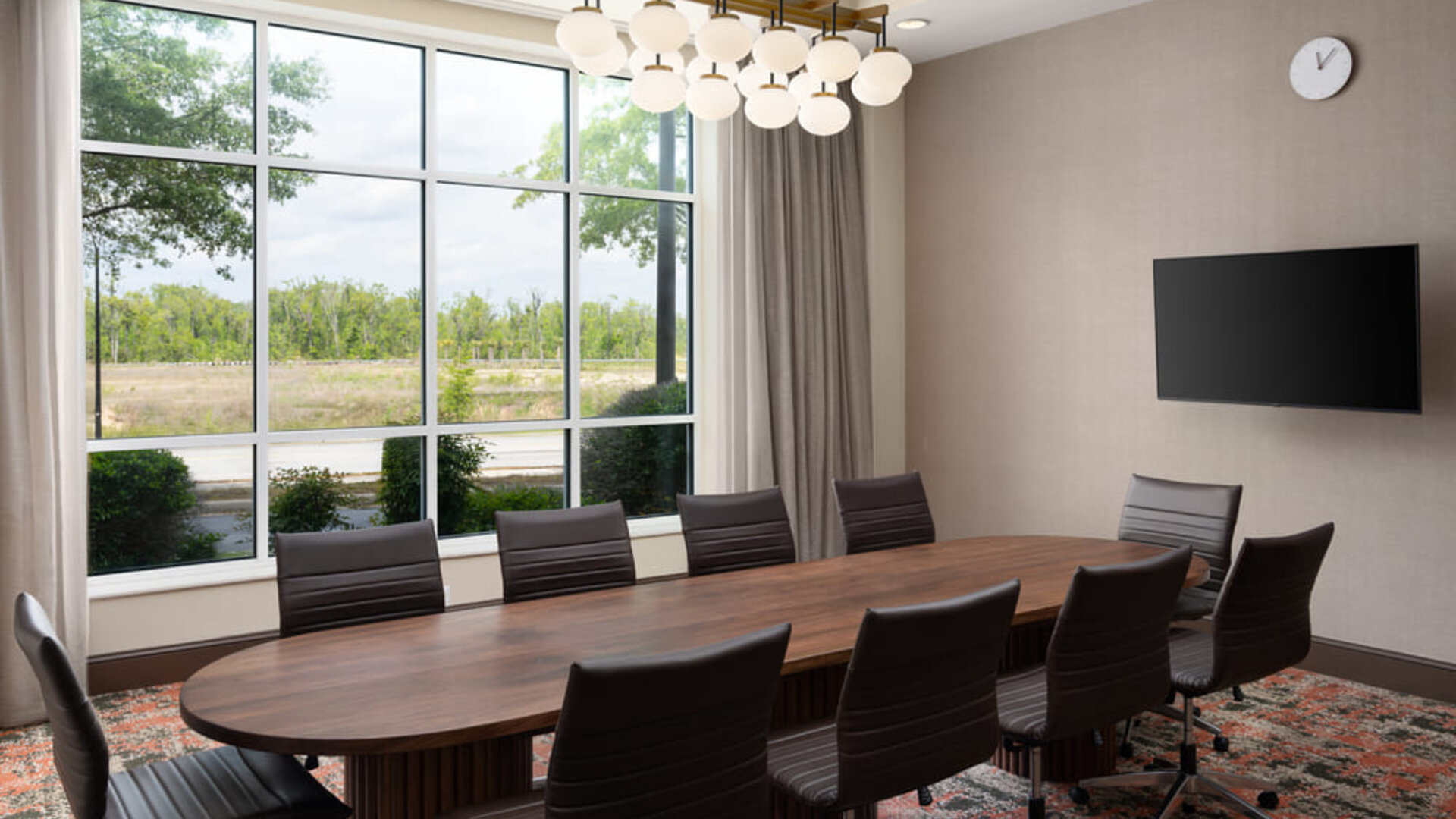 Executive boardroom with large conference table, ergonomic seating, and natural light for productive meetings at Embassy Suites By Hilton Charleston Airport Convention Center.