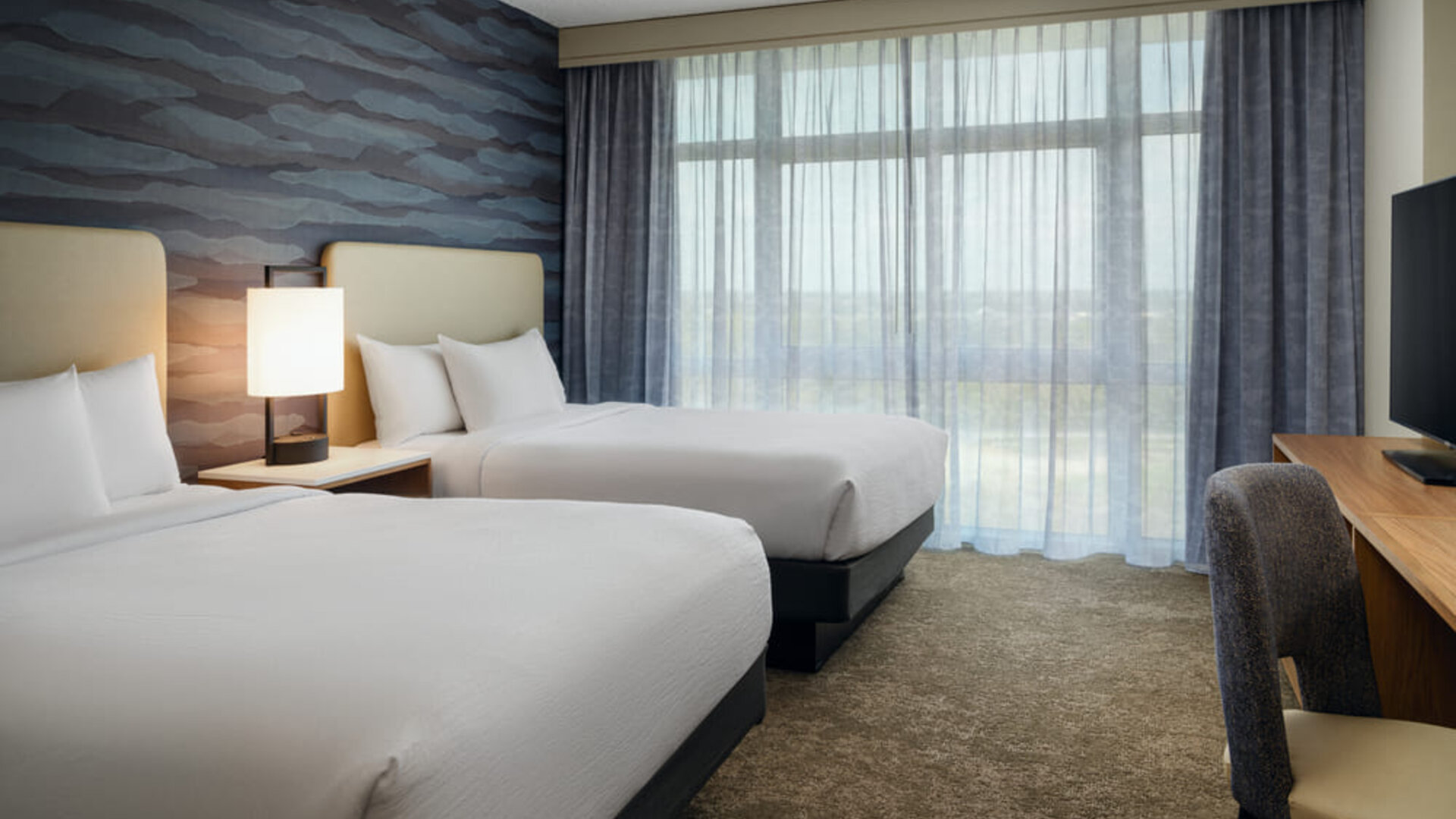 Guest room with two queen beds, modern amenities, and a comfortable atmosphere for families or groups at Embassy Suites By Hilton Charleston Airport Convention Center.